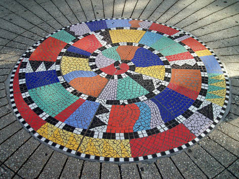 A colorful floor mosaic in a spiral pattern with geometric shapes inside